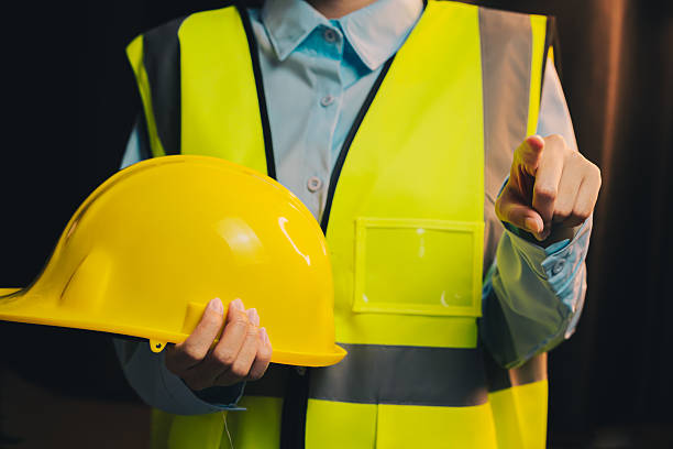 istock Engineer concept. Worker in Safety Vest Holding Yellow Hard Hat While Pointing to the Camera in a Studio Setting 2217999515