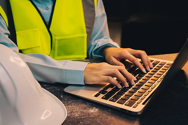 istock Engineer concept. Construction Worker in Safety Vest Using Laptop at Workplace with Hard Hat on Desk 2217999540