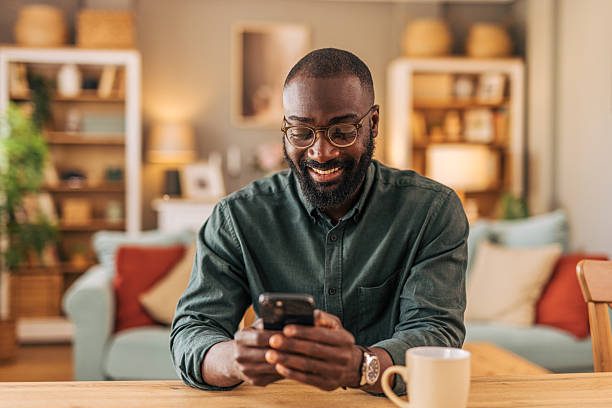 istock Smiling man using smartphone at home in living room 2218000430