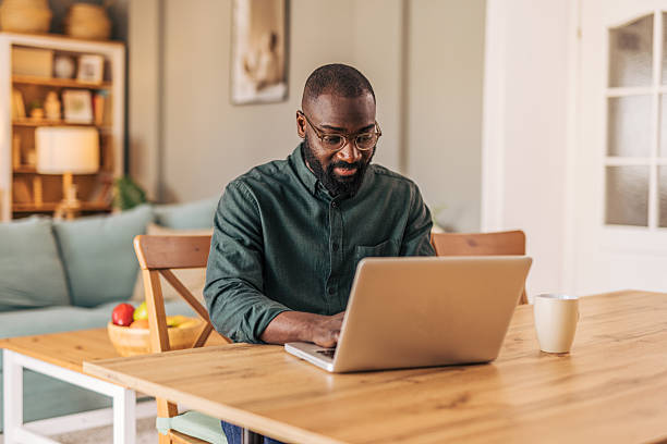 istock Focused black man working from home on laptop at dining table 2218000498