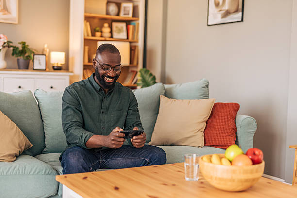 istock Smiling man playing mobile game on sofa at home 2218000741