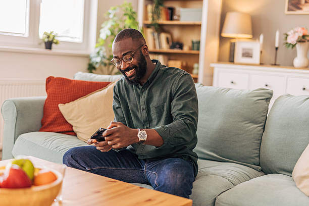istock Happy man playing videogames on mobile phone at home 2218000804