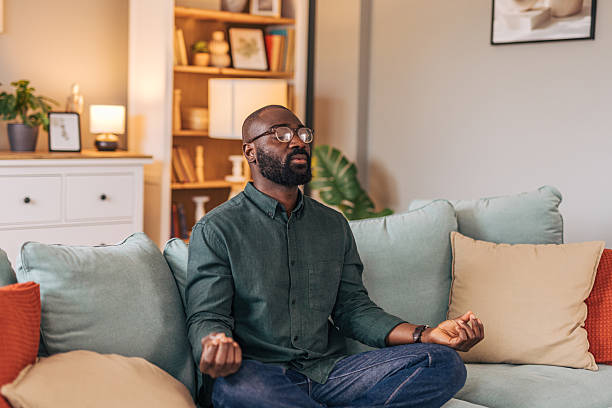 istock Serene man meditating on sofa in cozy living room 2218000867
