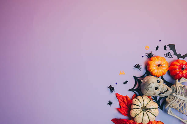 istock Halloween flat lay. Festive Halloween Decorations with Pumpkins, Skeletons, Spiders, and Fall Leaves on Purple Background 2218001523