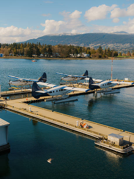 Seaplane and ferry in Vancouver harbor, Canada, highlighting alternative transportation methods with urban skyline and coastal mountains in the background.