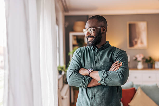 istock Smiling young man standing by the window with arms crossed 2218002161