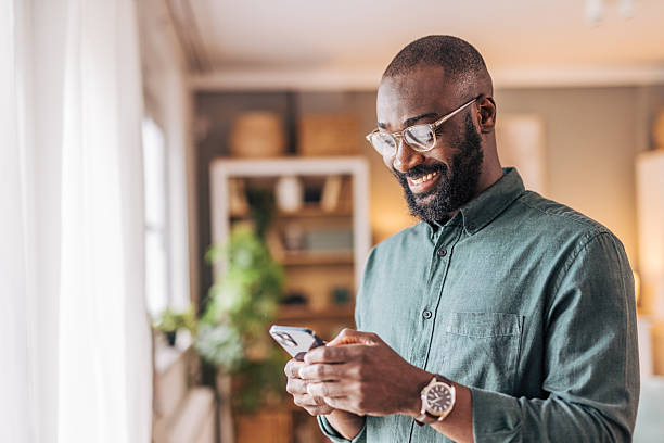 istock Smiling man using smartphone at home reading good news 2218002277