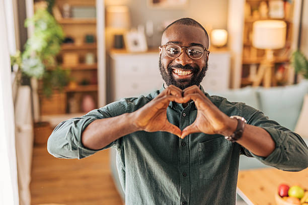 istock Happy man making heart shape with hands at home 2218002630