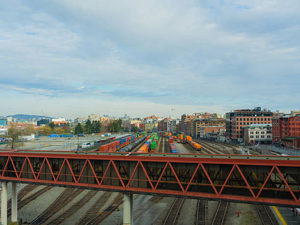 This vibrant photograph captures the bustling industrial port of Montreal, a critical node in Canadas trade network. In the foreground, a large cargo ship is anchored, its hull etched with the marks of international journeys. Behind it lies a tapestry of containers and dockside equipment, highlighting the busy logistics and transportation industry. The Montreal skyline, with its iconic high-rise buildings of the business district, stands proudly in the background, symbolizing the city's economic vitality. Autumn colors adorn the distant hills, contrasting the steel and concrete of urban progress with natural beauty. This scene showcases Montreals dual role as a historic yet contemporary hub for commerce and industry in Quebec.