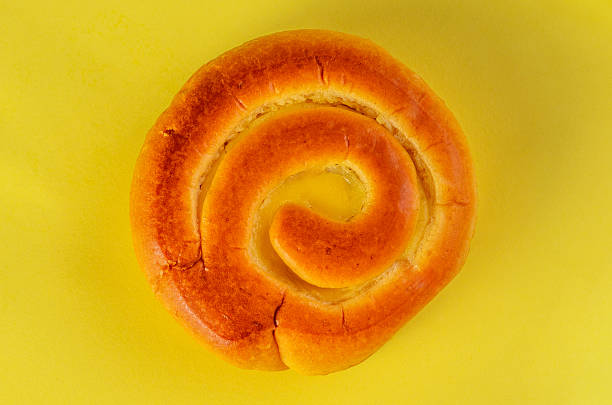 Golden swirl bun on yellow background angled view