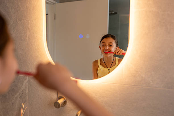 istock Girl Brushing Teeth in Bathroom Mirror 2218007752