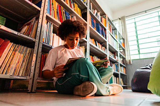 istock Focused schoolgirl reading alone in cozy school library corner 2218009804