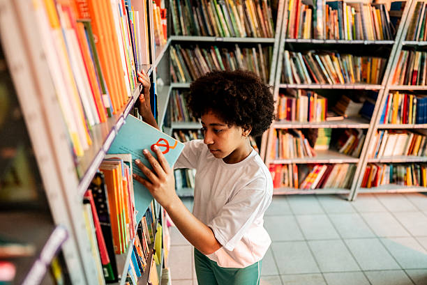 istock Schoolgirl choosing book in school library 2218010045
