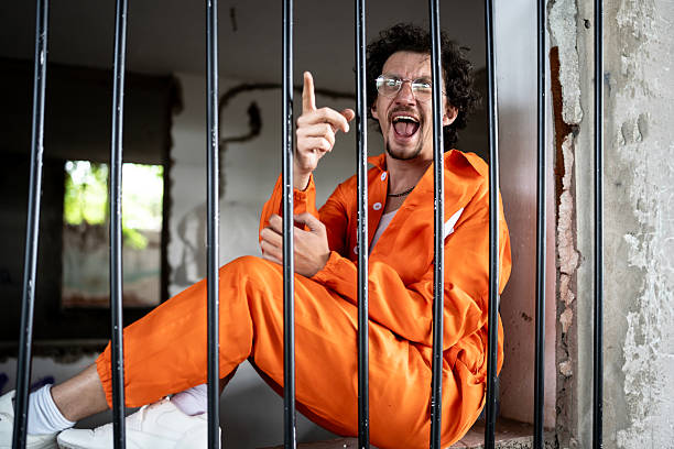 Lively individual in an orange jumpsuit sitting in a jail cell with expressive emotions. The scene captures a unique moment of humor or irony despite the serious context of incarceration.