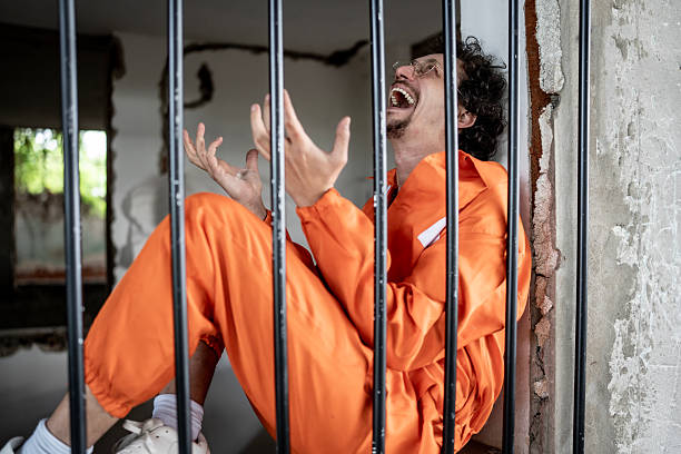 istock Man in Orange Jumpsuit Crying Inside Jail Cell Behind Bars 2218010100