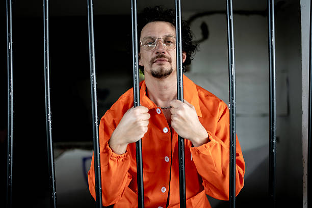 istock Man in Prison Uniform Behind Bars Showing Emotions and Introspection 2218010124