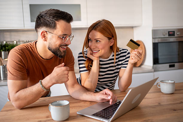 istock Happy couple making online payment using laptop and credit card in kitchen 2218016845