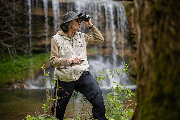istock Ecologist Birdwatching Near Waterfall In Spring Forest 2218017524