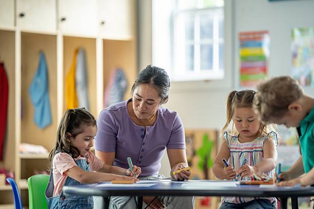 istock Teacher Assisting Young Children With Creative Activities in a Classroom Environment 2218038507