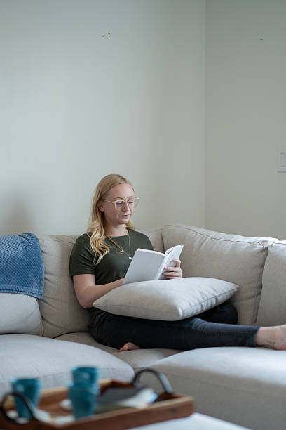 Woman Relaxing on a Sofa While Reading a Book in a Cozy Space
