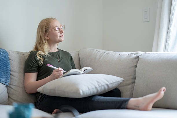 istock Young Woman Relaxing on Couch While Writing in a Journal 2218040858