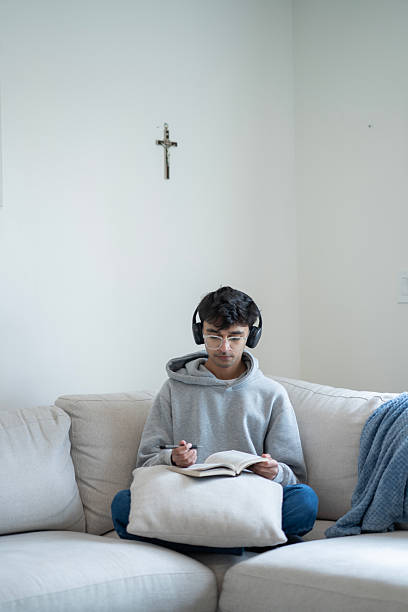 istock Young Man Studying with Headphones on a Comfortable Sofa 2218041981