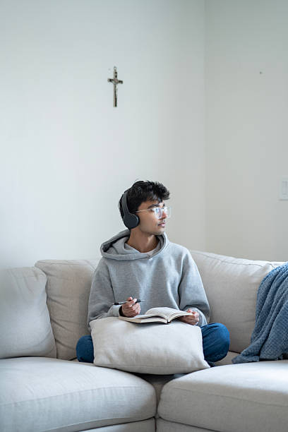 istock Young Individual Reading Book While Wearing Headphones in a Peaceful Home Setting 2218041982