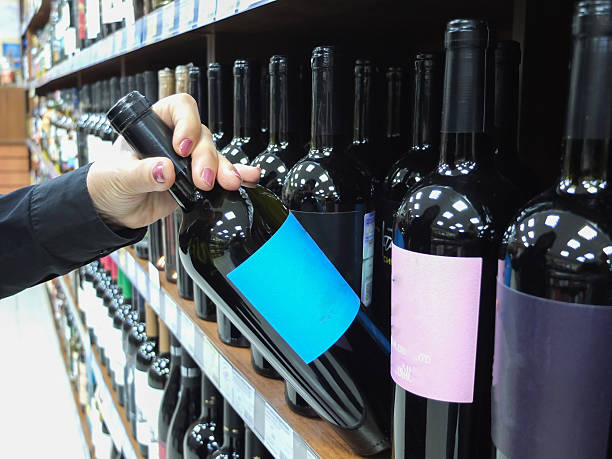 istock woman choosing wine in a market, display case with various drinks 2218047281