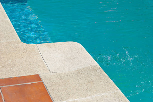 vibrant turquoise swimming pool water with elegant stone coping and terracota tiles, summer background concept