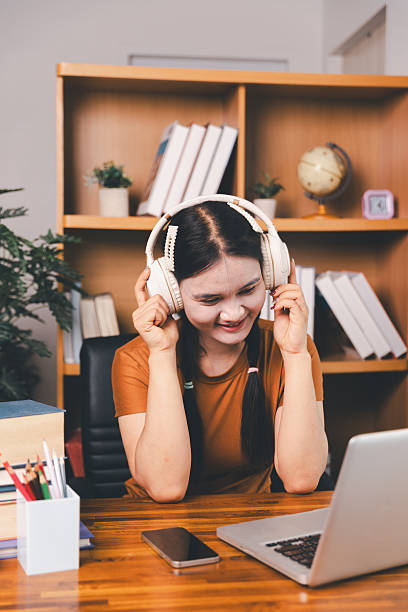 istock Asian girl doing homework and studying at home. woman using laptop at desk write notes watching webinar, study online, look at learn web class or having virtual call meeting remote working from home. 2218053244