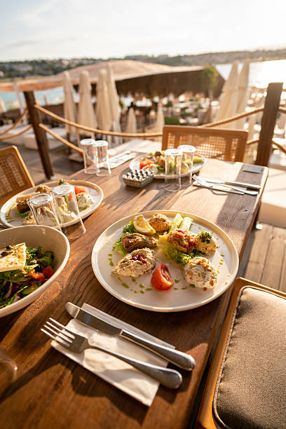 aegean appetizers are on table on foreground focus on foreground in restaurant and beach is background vertical food and drink still stock photo