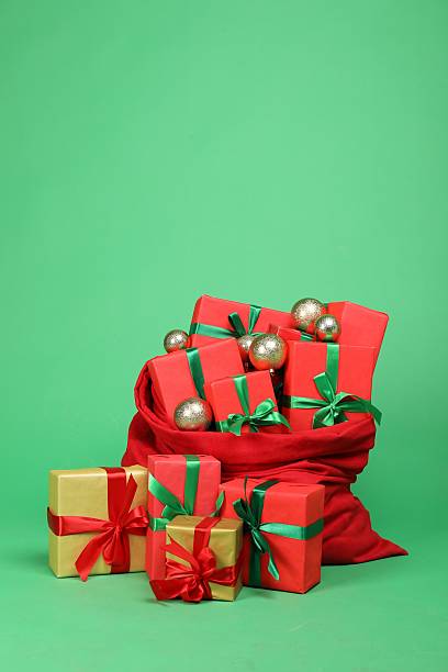 istock Red Santa Claus bag with baubles and gift boxes on green background 2218054157
