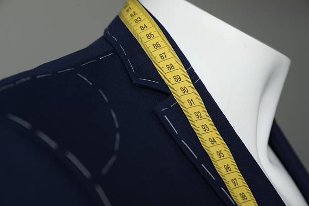 istock Semi-ready jacket with tailor's measuring tape on mannequin against grey background, closeup 2218054689