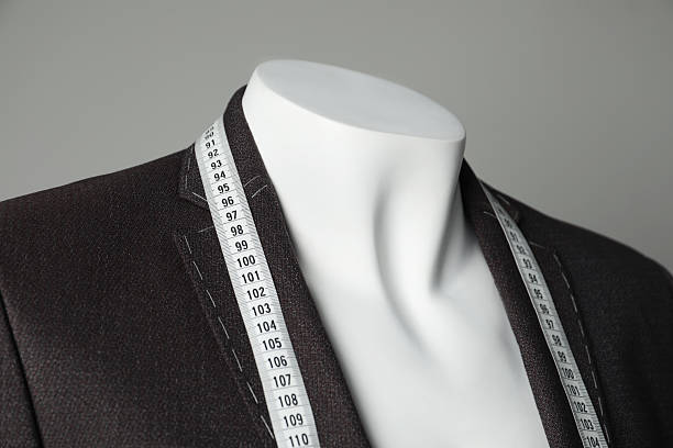 istock Semi-ready jacket with tailor's measuring tape on mannequin against grey background, closeup 2218054690