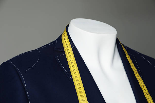 istock Semi-ready jacket with tailor's measuring tape on mannequin against grey background, closeup 2218054703