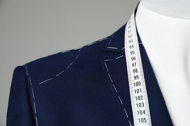 istock Semi-ready jacket with tailor's measuring tape on mannequin against grey background, closeup 2218054709