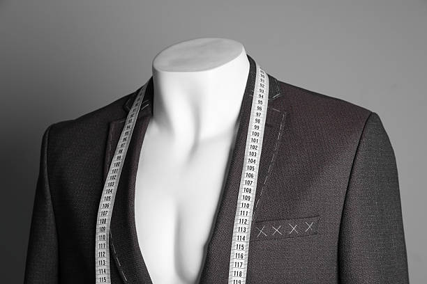 istock Semi-ready jacket with tailor's measuring tape on mannequin against grey background, closeup 2218054713