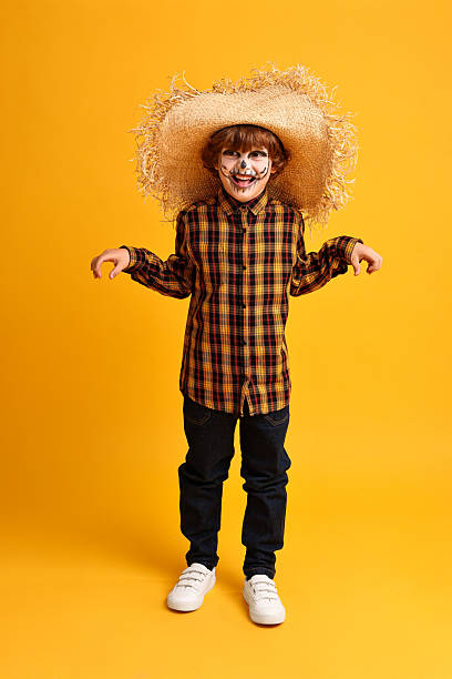 istock Funny boy dressed like scarecrow on yellow background. Halloween celebration 2218055186