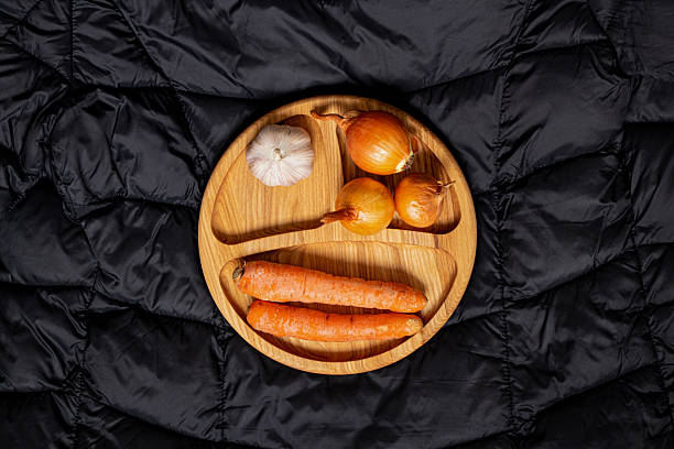 Wooden plate with onion, garlic and carrot on black background, natural vegetables for cooking stock photo
