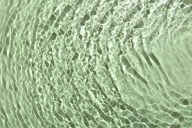 istock Rippled surface of clear water on light green background, top view 2218055506
