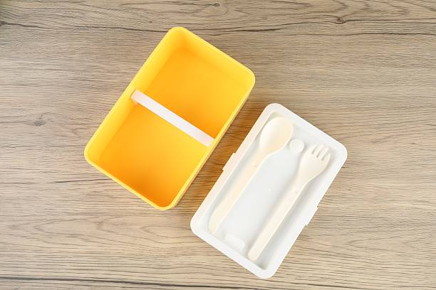 Empty plastic lunch box with cutlery on wooden table, top view