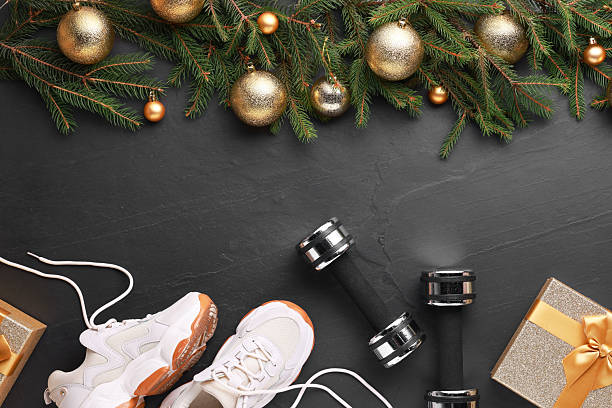 istock Dumbbells, gift box, sneakers and Christmas decor on black background, flat lay 2218056849