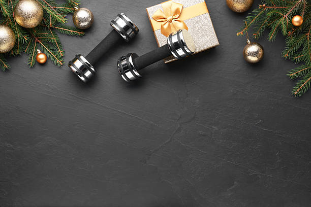 istock Dumbbells, gift box and Christmas decor on black background, flat lay. Space for text 2218056862