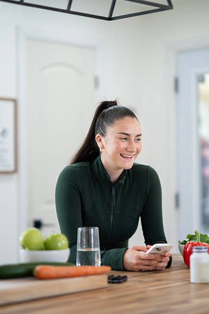 istock Smiling Woman Using Smartphone in Modern Kitchen Maintaining a Healthy Lifestyle 2218056920
