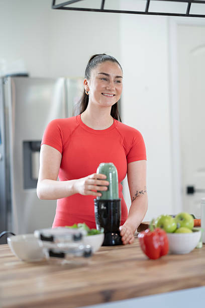istock Smiling Woman Preparing Healthy Smoothie in a Modern Kitchen 2218057249