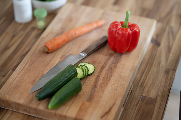 A wooden cutting board displays fresh vegetables and a knife, featuring vibrant colors and a focus on healthy food preparation or cooking. Perfect for culinary, health, and nutrition concepts.