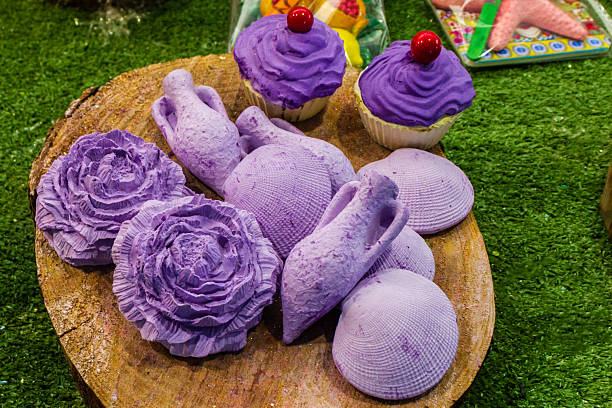 istock Purple Decorative Objects and Cupcakes Displayed on Wooden Surface With Green Background 2218059318
