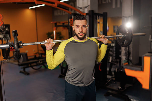 Handsome young man lifting weights while working out in the gym