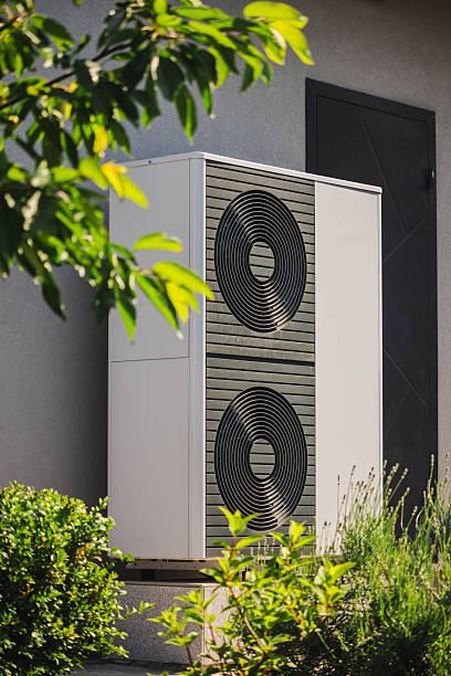 istock Modular heat pump unit for home heating and cooling installed next to a residential wall, surrounded by decorative plants and garden landscaping 2218067411