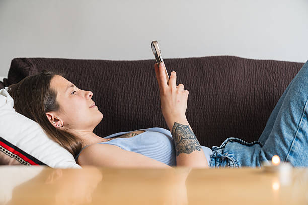 istock Young woman relaxing on sofa using smartphone at home 2218073480